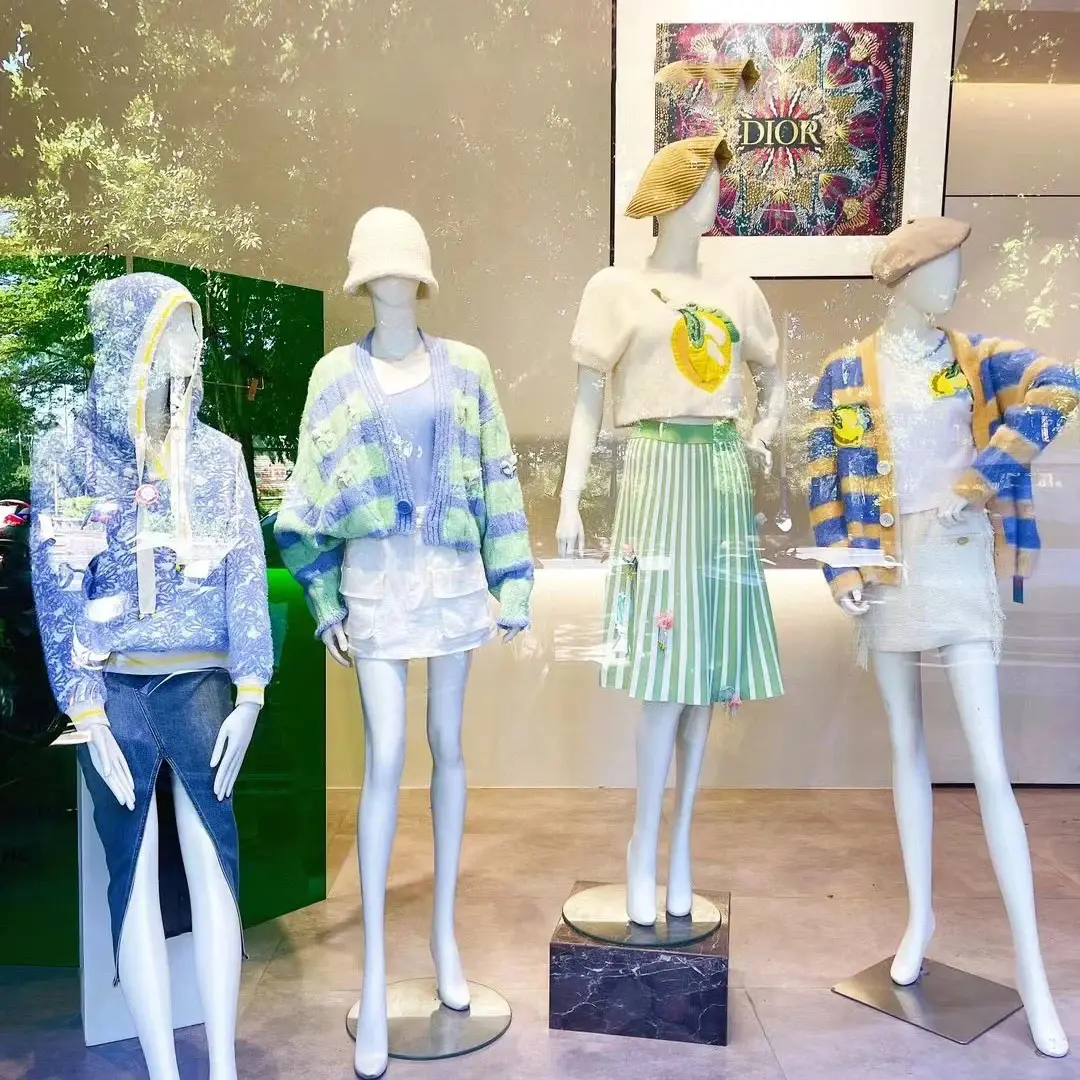 “Bốn mannequin mặc thời trang xuân hè nữ tính và năng động, phối hợp áo cardigan, chân váy và mũ nồi trong không gian trưng bày của thương hiệu