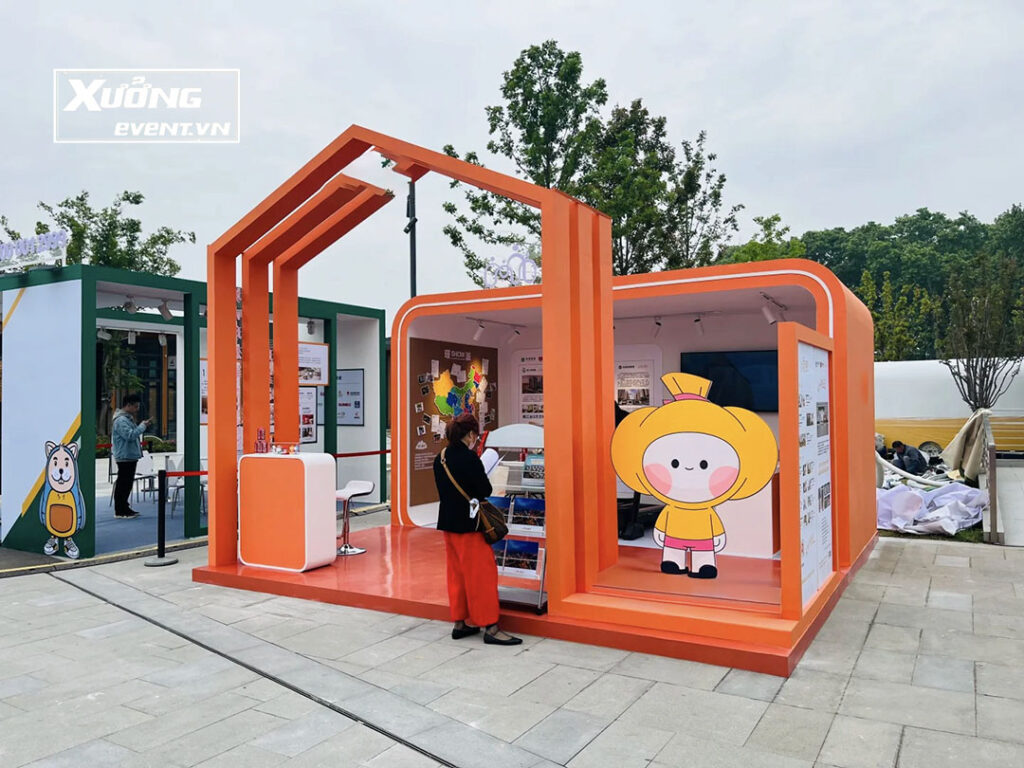 Gian hàng triển lãm ngoài trời hiện đại với thiết kế mở, màu sắc nổi bật và hình ảnh mascot thương hiệu